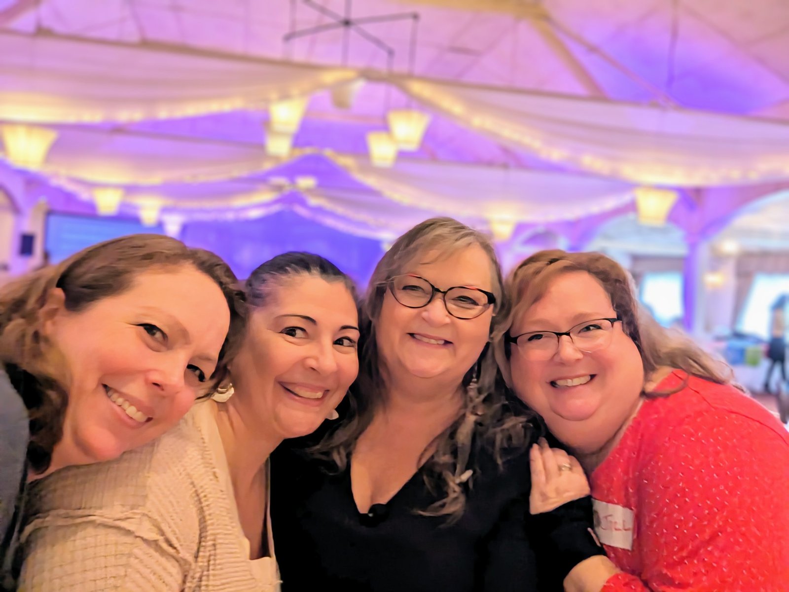 Four women smiling closely together at a women's event in Ontario, Canada