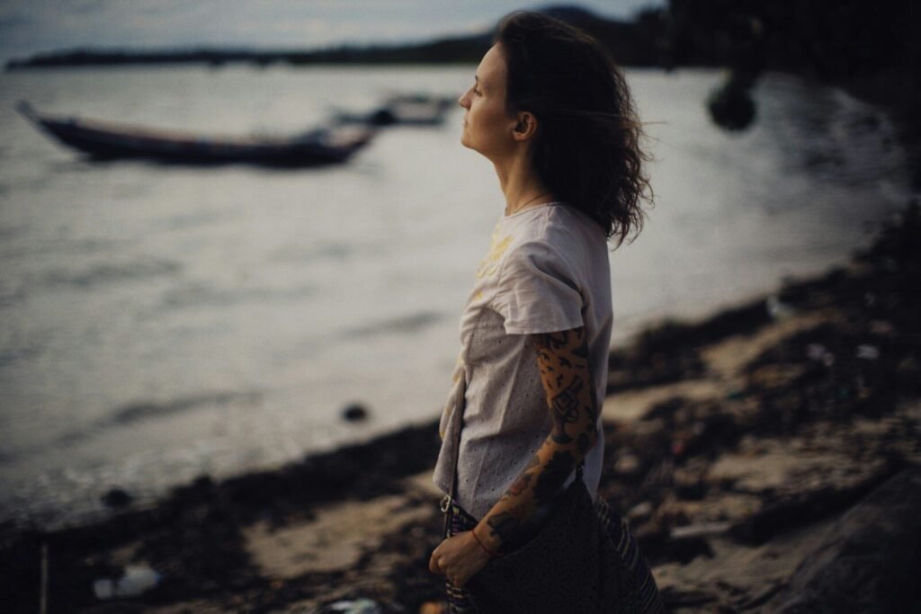 a woman standing on a beach next to a body of water