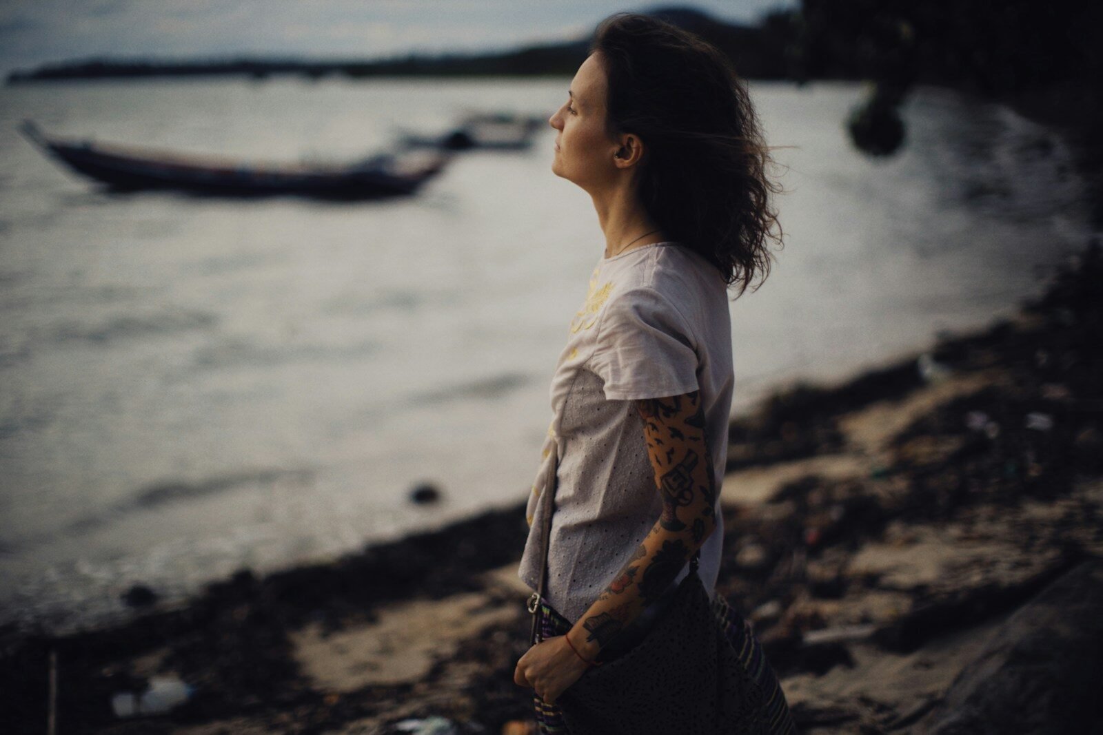 a woman standing on a beach next to a body of water